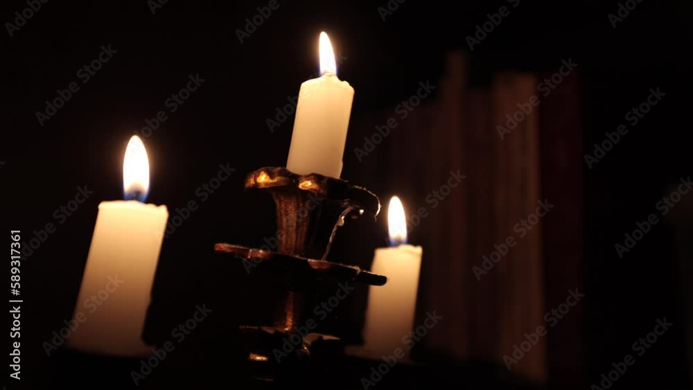 Candles and a bookshelf. Candles in the dark. Illumination of books on the shelf. Reading by candlelight. The mystical atmosphere of the library, for documentary projects and not only Candles and a bookshelf. Candles in the dark. Illumination of books on the shelf. Reading by candlelight. The mystical atmosphere of the library, for documentary projects and not only