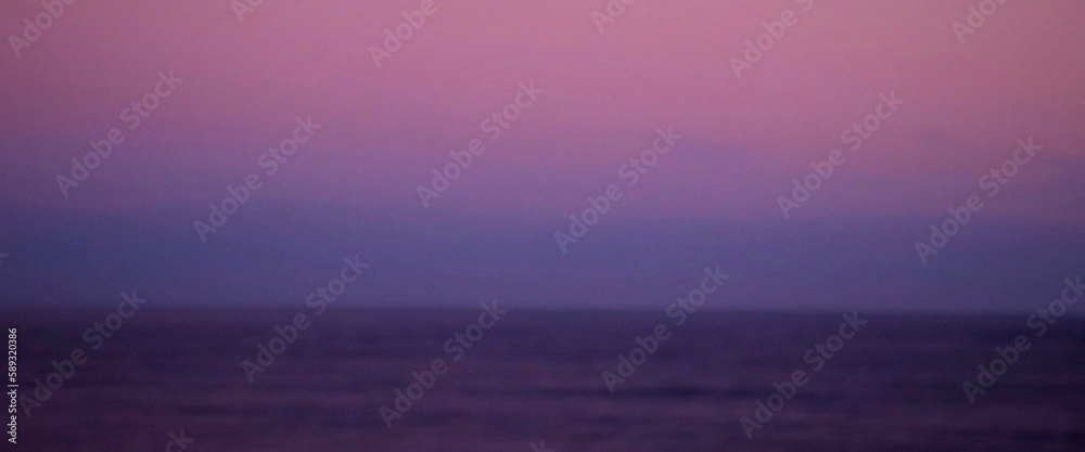 Calming picture of a reddish sky at sunrise over a calm ocean water