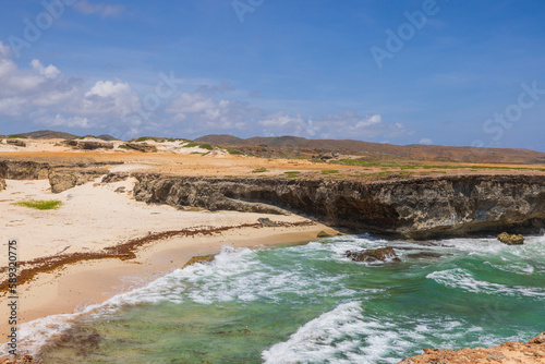 Beautiful ocean coastline landscape view. Blue-green water, yellow sand and blue sky. Aruba. 