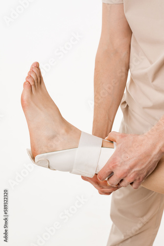 Traumatologist puts external ankle or foot bandage on leg to recover from injuries and reduce risk of new injuries. Ankle and foot external orthosis to reduce pathological mobility of ankle joints.