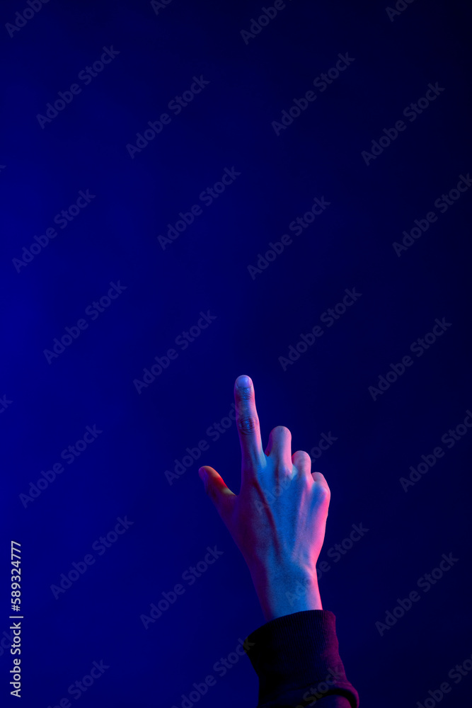 Fototapeta premium Asian man pointing finger in studio with blue light with copy space