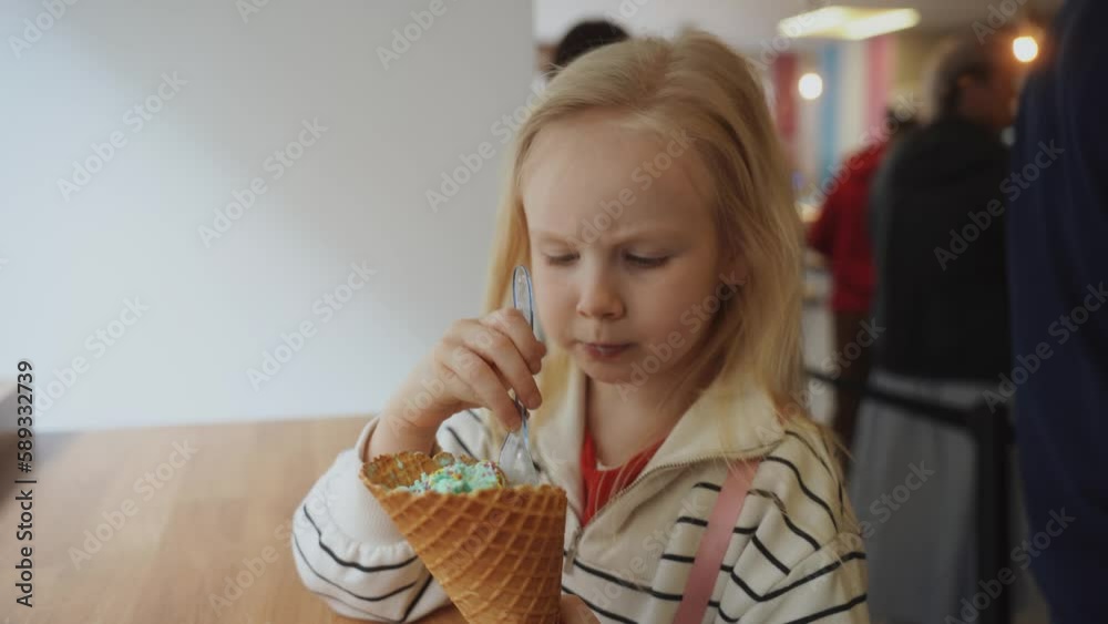 Cute little girl eating ice cream in a cafe in a white sweater. Kilkenny, 2023 Cute little girl eating ice cream in a cafe in a white sweater. Kilkenny, 2023