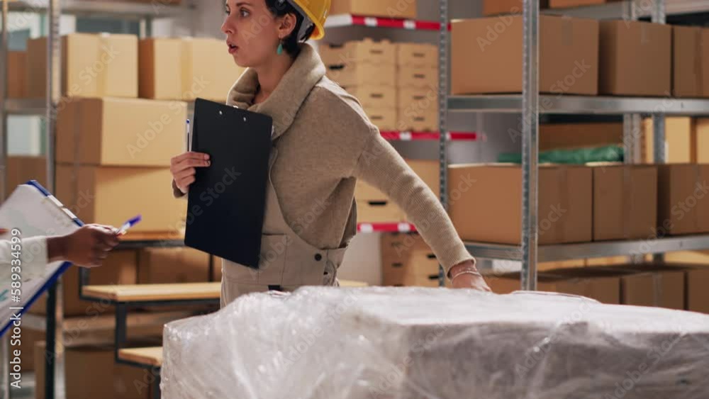 Two women analyzing list of products in warehouse to work on stock