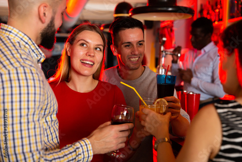 Portrait of happy young woman with colleagues enjoying corporate party in bar. High quality photo