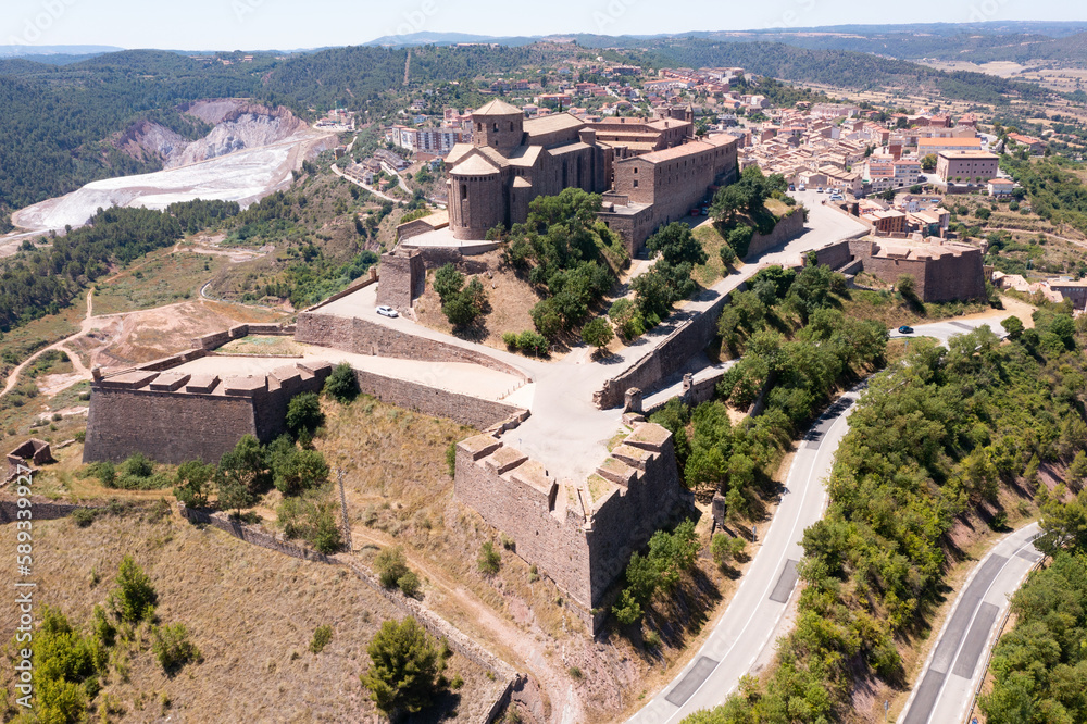 Picturesque aerial view of walled fortified castle of Cardona located on hill in Cardener river valley on background of townscape on summer day, Catalonia, Spain
