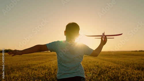 Child aviator. Boy wants to become pilot, astronaut. Slow motion. Happy kid runs with toy airplane on field in sunset light. Children play toy airplane. Teenager dreams of flying and becoming pilot.
