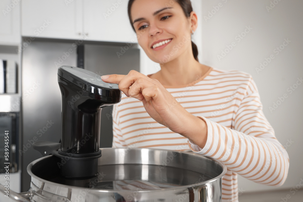 Woman using thermal immersion circulator in kitchen, focus on hand. Sous vide cooking Woman using thermal immersion circulator in kitchen, focus on hand. Sous vide cooking
