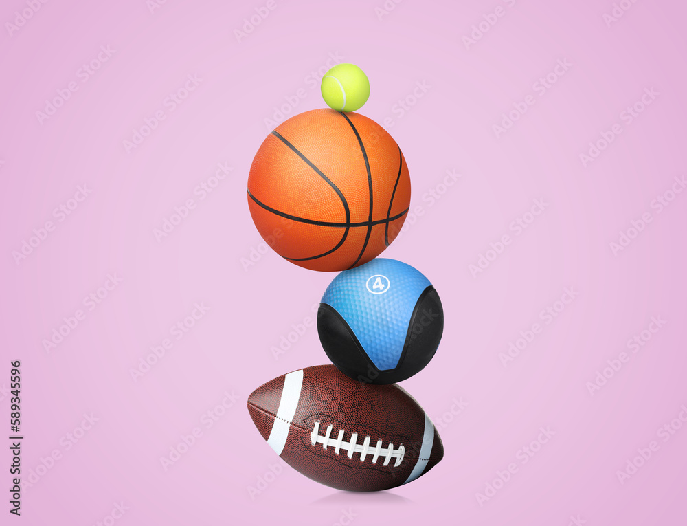 Stack of different sport and medicine balls on light violet background Stack of different sport and medicine balls on light violet background