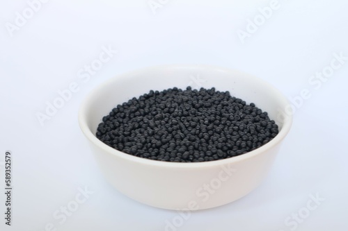 Plastic pellets for production, plastic polymer dye granules color black on white background.