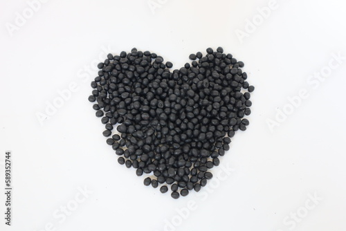Plastic pellets for production, plastic polymer dye granules color black  on white background.