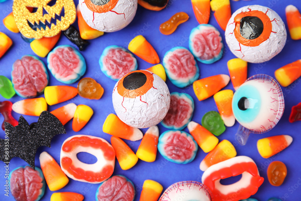Delicious bright candies on blue background, flat lay. Halloween sweets