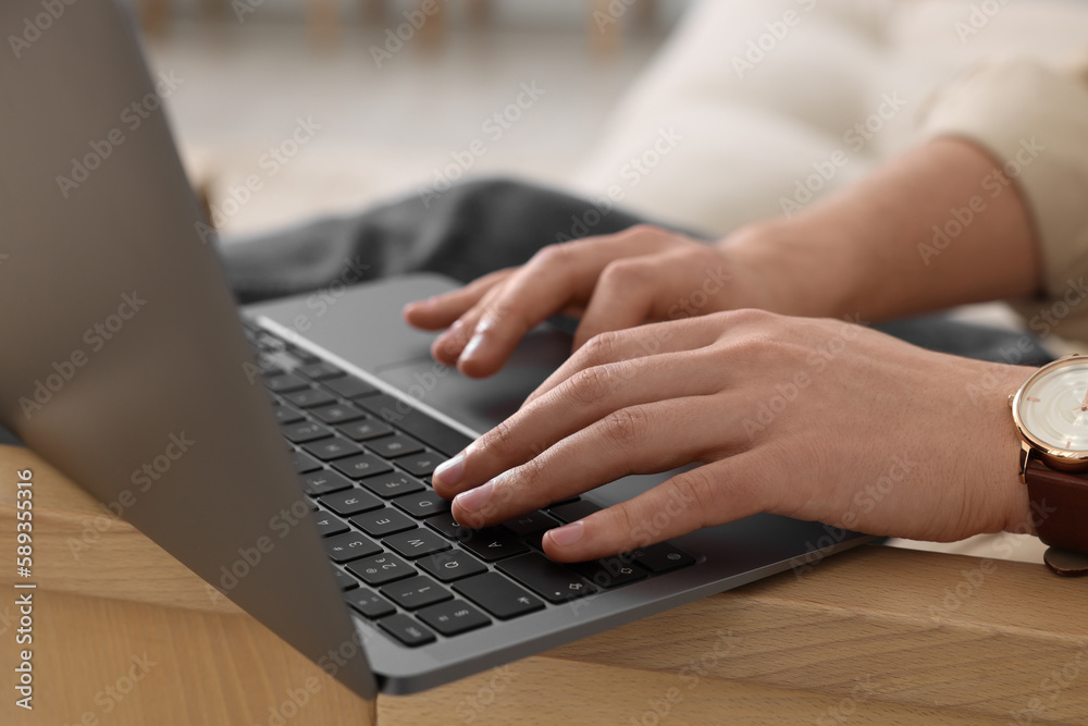 Man working on laptop at wooden table indoors, closeup Man working on laptop at wooden table indoors, closeup