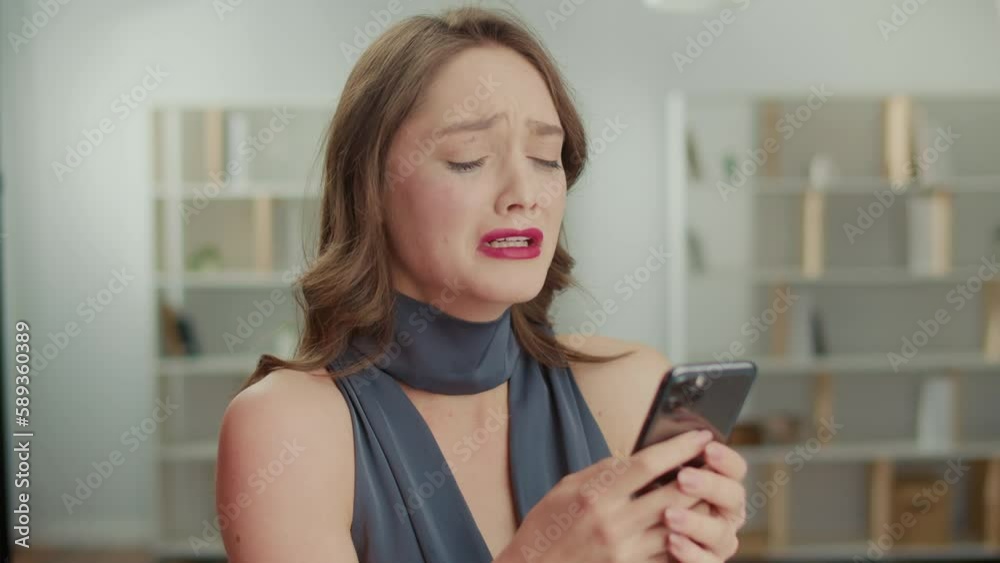 A Depressed Young Woman is Crying While Looking at Her Mobile Phone. A Sad Woman is Sobbing and Wiping Tears, Texting on the Phone, and Feeling Heartbroken. Emotional pain and trauma. A Depressed Young Woman is Crying While Looking at Her Mobile Phone. A Sad Woman is Sobbing and Wiping Tears, Texting on the Phone, and Feeling Heartbroken. Emotional pain and trauma.