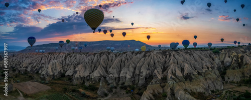 Sunrise panorama of famous Cappadocia landscape view with lots of hot air balloons flying