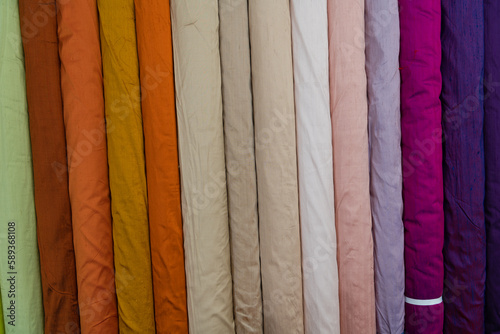 Collection of fashionable fabrics. Samples of different natural fabrics for sewing a fashion collection of clothes. Large selection of fabrics in the store or tailor warehouse.