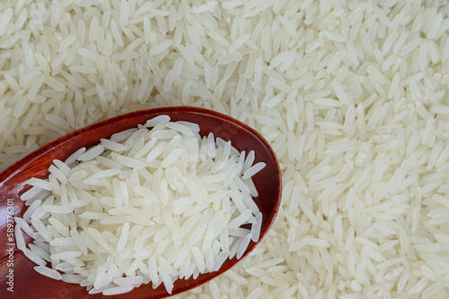 White rice, jasmine rice, on a wooden spoon, placed on top of the grain.