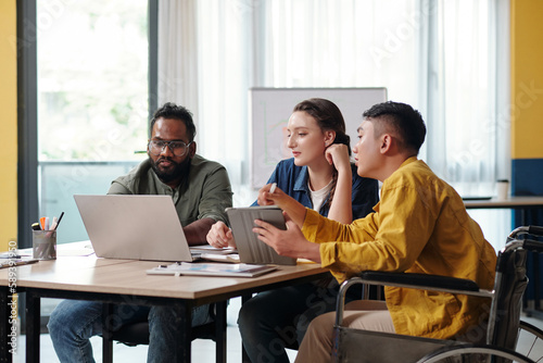 Diverse business team watching product presentation on laptop screen at meeting photo