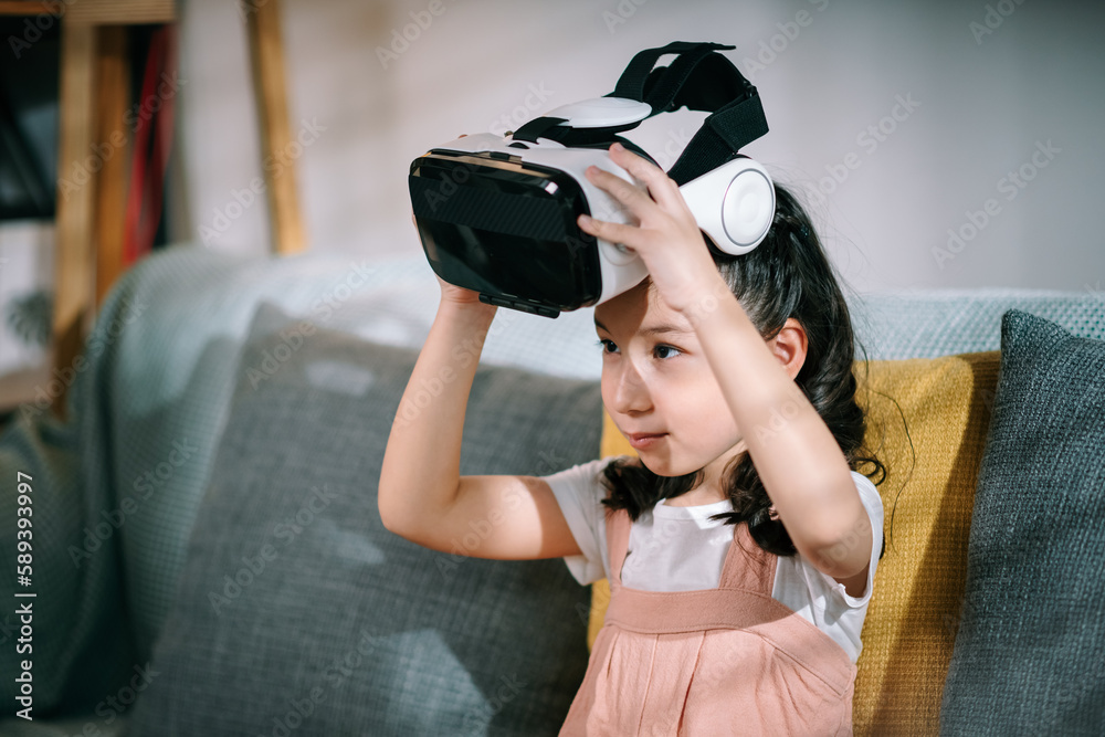 Little girl wearing virtual reality headsets for watching movie on sofa
