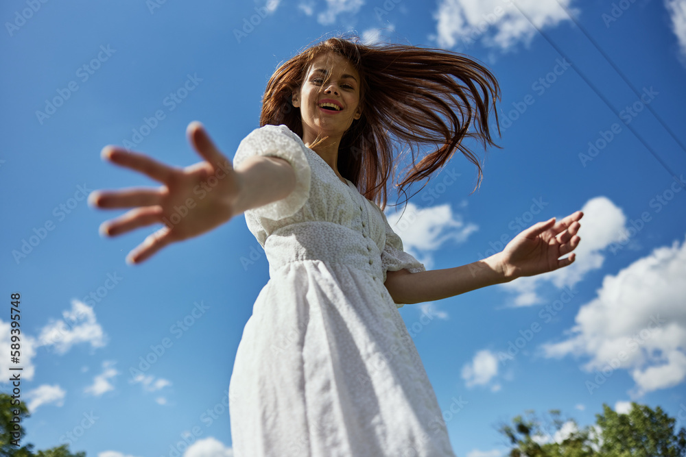 happy red-haired woman offer one's hand her hand to the camera while standing against the background of a blue sky with clouds happy red-haired woman offer one's hand her hand to the camera while standing against the background of a blue sky with clouds