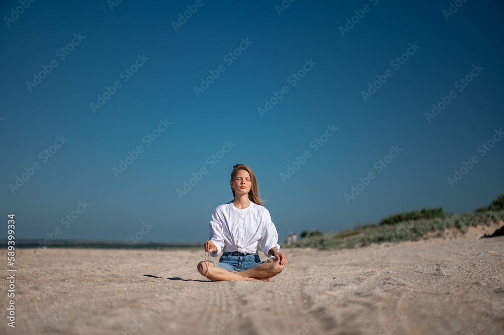 Girl meditating by the sea. Wind shakes long blond hair Girl meditating by the sea. Wind shakes long blond hair