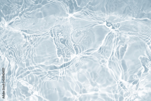 Water waves surface hits the sunlight. Close up swimming pool water background. Transparent water surface.