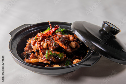 local cook live fresh catfish meat with spicy red dry chili asam sauce in big black claypot on wood table asian Chinese banquet halal seafood steamboat menu  photo