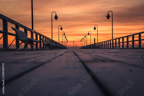 Fototapeta Naklejka Na Ścianę i Meble -  Beautiful sunrise over the Polish sea. Popular pier on the Baltic Sea at sunrise. Shallow depth of field photo with foreground blur effect.