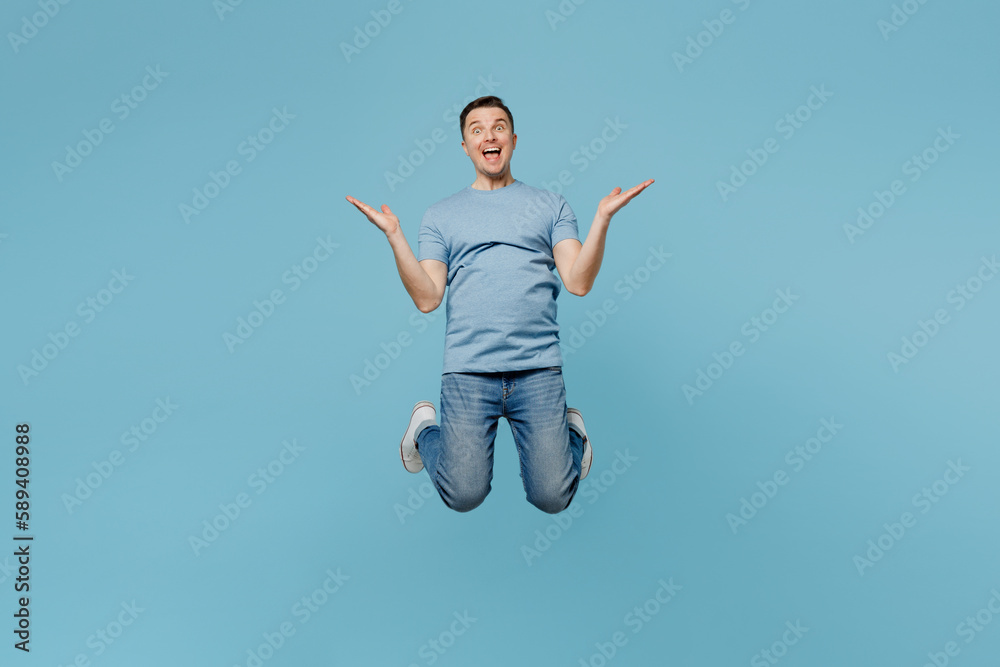 Full body young overjoyed cheerful fun winner smiling happy man wearing casual t-shirt jump high spreading hands isolated on plain pastel light blue cyan background studio portrait. Lifestyle concept. Full body young overjoyed cheerful fun winner smiling happy man wearing casual t-shirt jump high spreading hands isolated on plain pastel light blue cyan background studio portrait. Lifestyle concept.