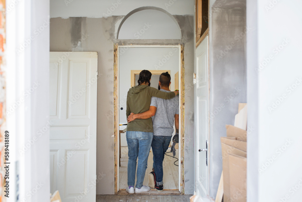 Couple standing in doorway and looking at apartment during renovation Couple standing in doorway and looking at apartment during renovation