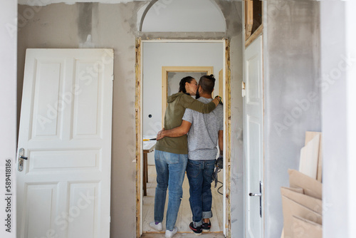 Couple standing in doorway and kissing during apartment renovation