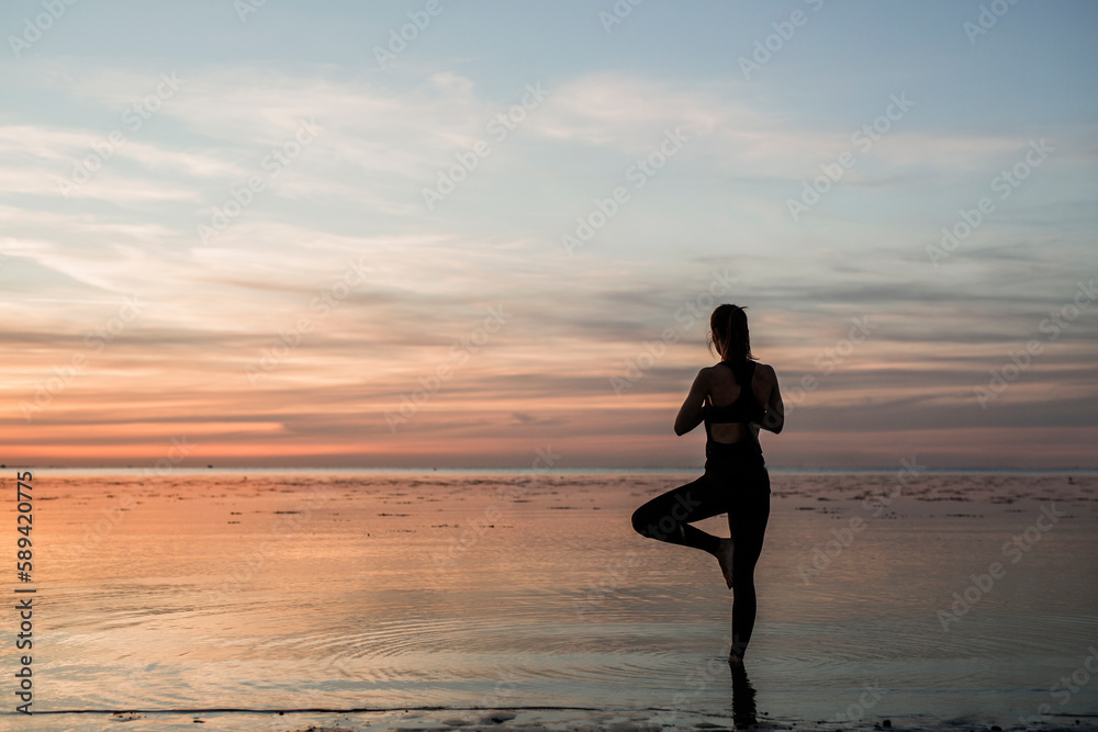 Young woman doing yoga on beach at sunset Young woman doing yoga on beach at sunset