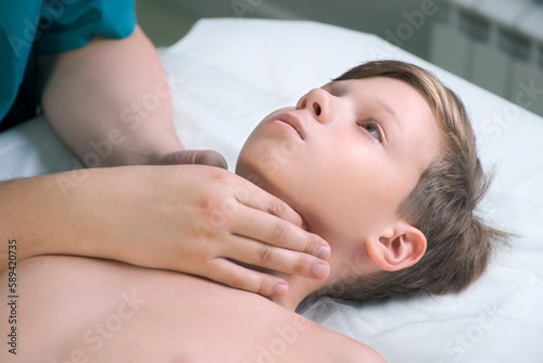 Session of craniosacral therapy  cure of teen boy s jaw and neck by a doctor therapist. Craniosacral therapist touches the boy s cheeks and checks the correctness of the jaws at the hospital.
