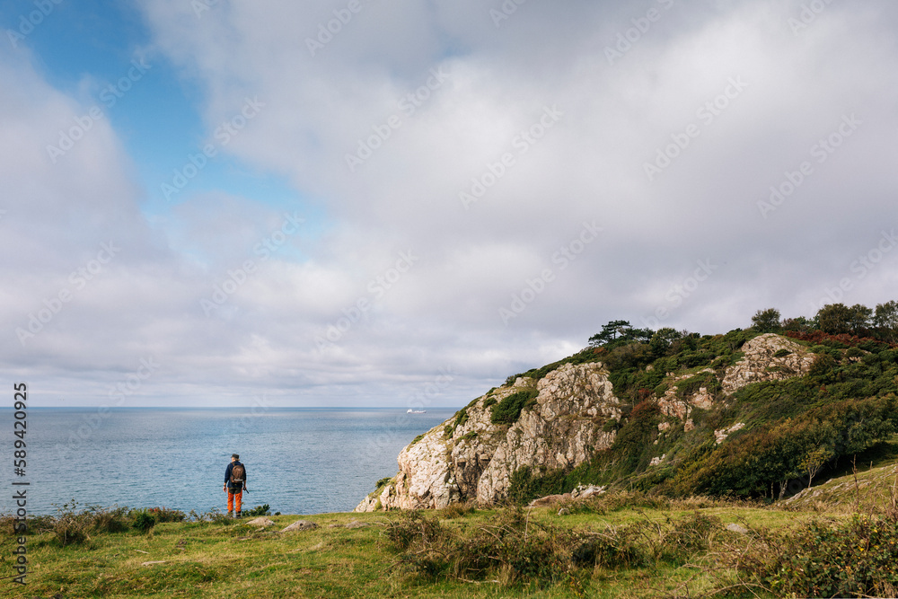 Man standing near cliffs by sea Man standing near cliffs by sea