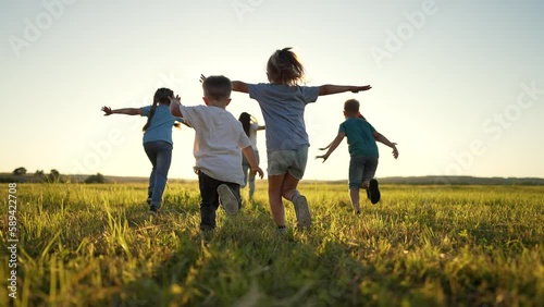Happy holiday in nature. Family and friend run together on green grass in summer.Active children walk in the park at sunset.Child have fun play and run in spring in field.Family picnic on green grass. photo