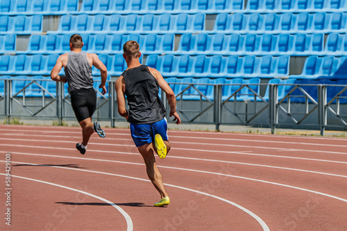 back two decathlon athletes running sprint race track, summer athletics championships at stadium photo