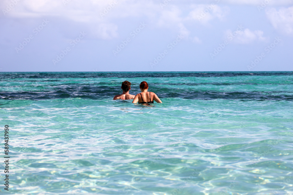 Couple swimming in azure sea water. Man with woman together, beach vacation