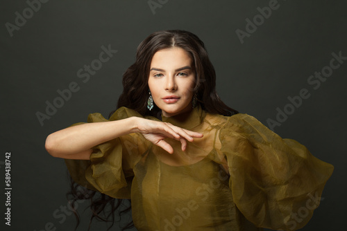 Fashion beauty portrait of beautiful elegant brunette model woman in earring against black studio wall background