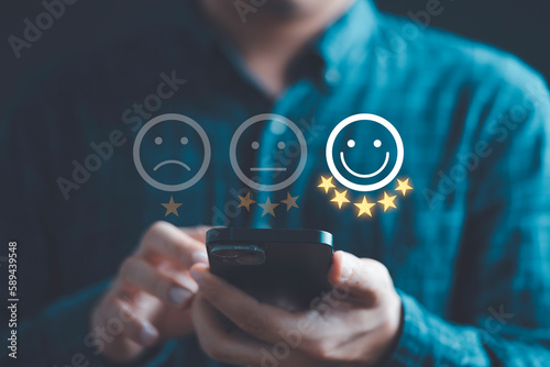 Bilde på lerret Businessman using smartphone to give five glowing golden stars and smile face icon for excellent evaluation survey after client use product and service from customer satisfaction concept