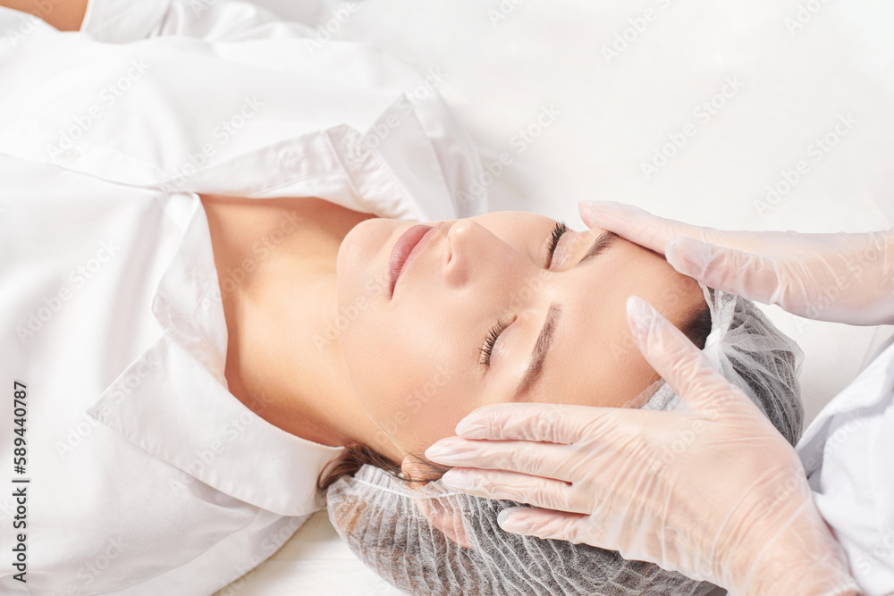 Foto de Beautician massages woman face skin after rubbing moisturizing