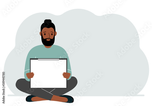 A man sits crossing his legs and holds a clipboard with a white read sheet for the text in his hands.