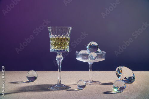 A glass of champagne wine or yellow beverage displayed with a glass containing diamond sphere on dark background