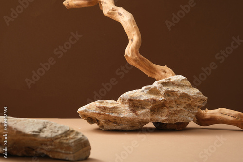 Against a brown background, big tree branch and some block of stone are decorated. Concept for natural, organic beauty products.
