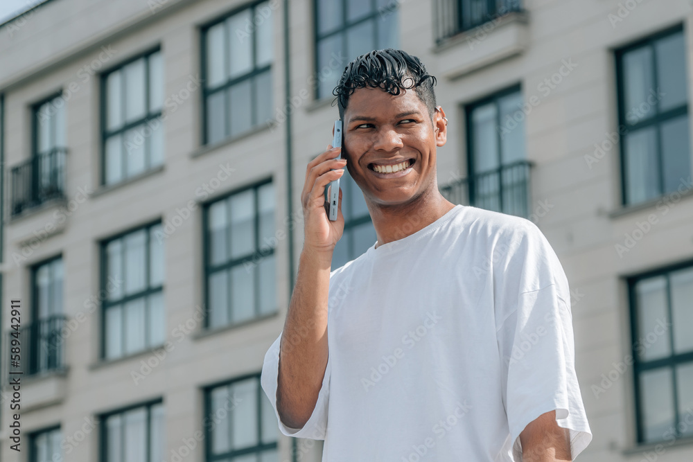 young latin man with mobile phone in the city street