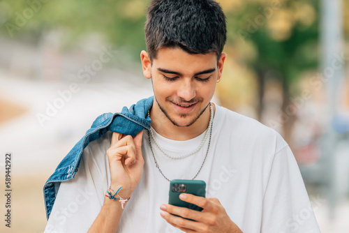 young male on the street walking looking at the mobile phone or smartphone