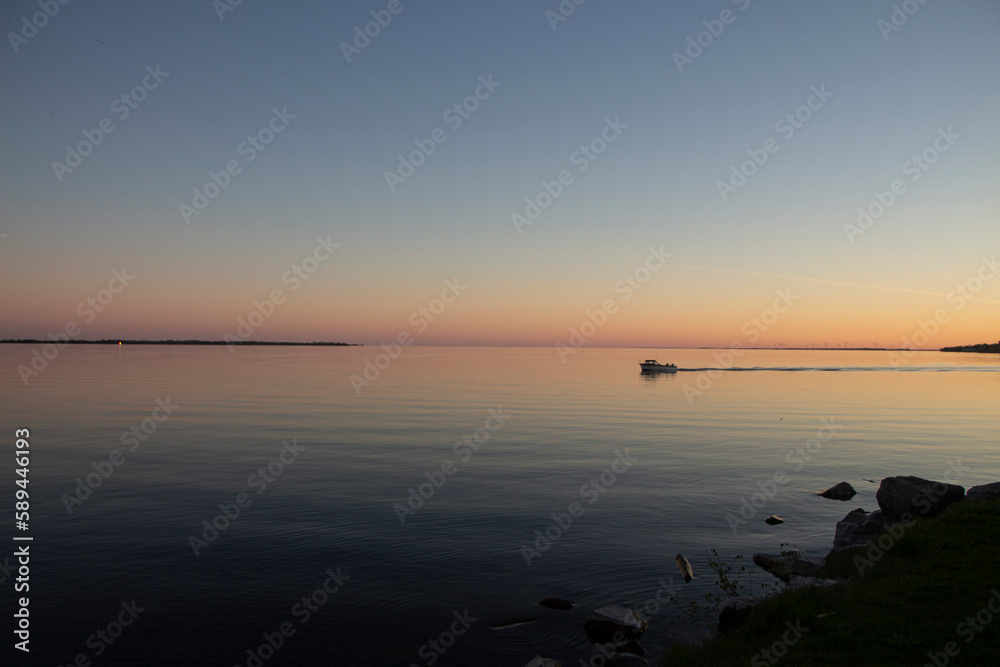 Naklejka premium Little boat in the sunset over the lake