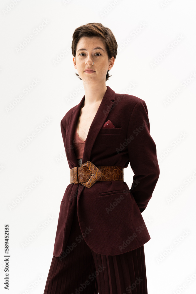 young brunette woman in fashionable blazer with leather belt looking at camera on white background. young brunette woman in fashionable blazer with leather belt looking at camera on white background.