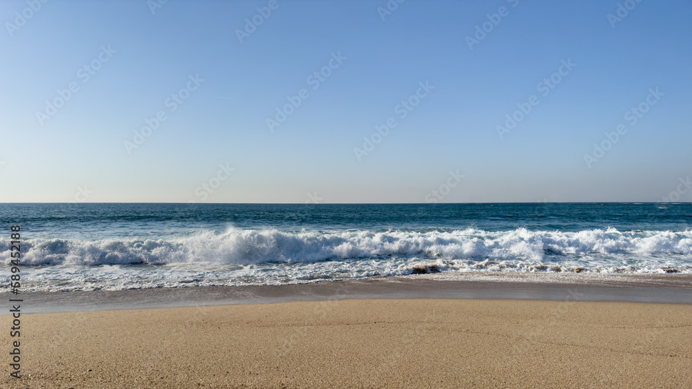 Waves breaking on empty beach on a clear spring day in Povoa de Varzim, Portugal.