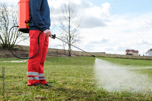 Canvas Print Farmer spraying pesticide on lawn field wearing protective clothing