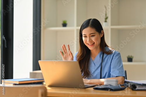 Friendly medical professionals wearing blue scrubs giving consultation to patient on laptop. Therapist online, telemedicine concept