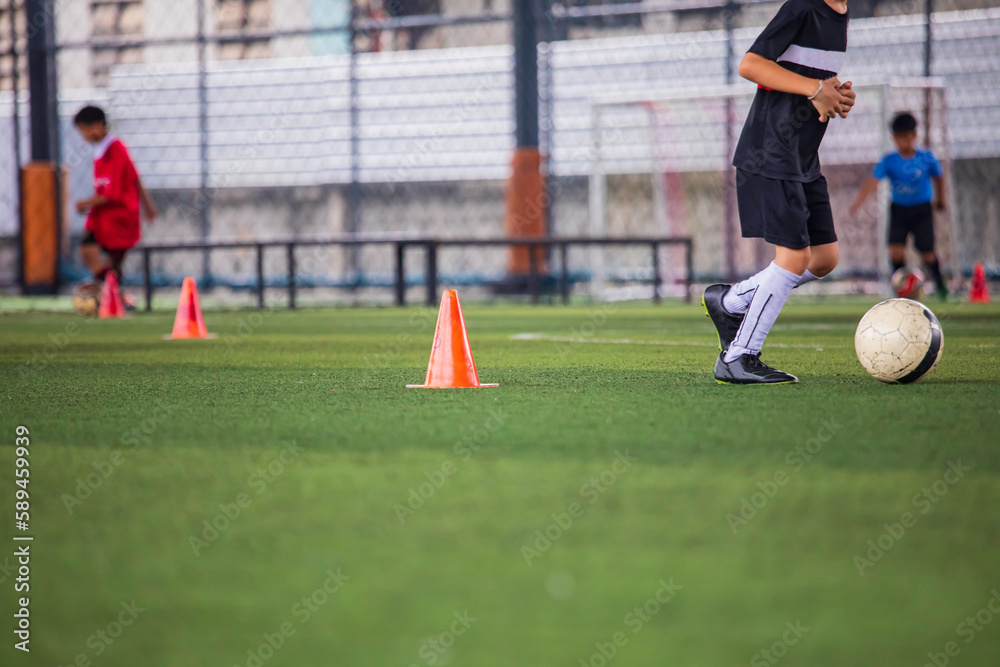 Obraz premium Children playing control soccer ball tactics cone on a grass field with for training background